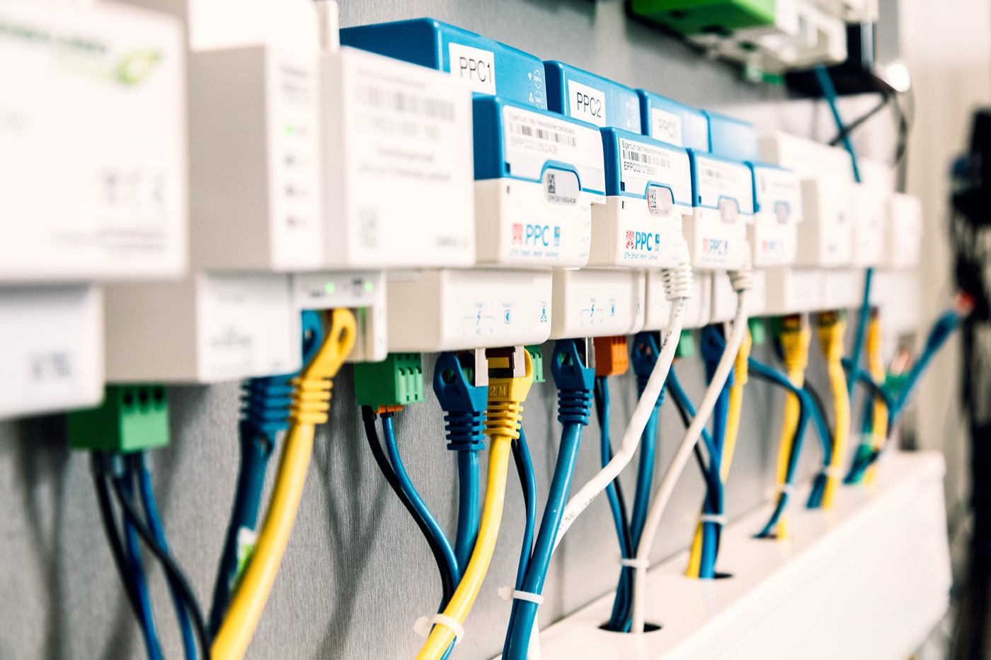 A DIN rail of smart meter gateways and control devices, wired up with patch cables